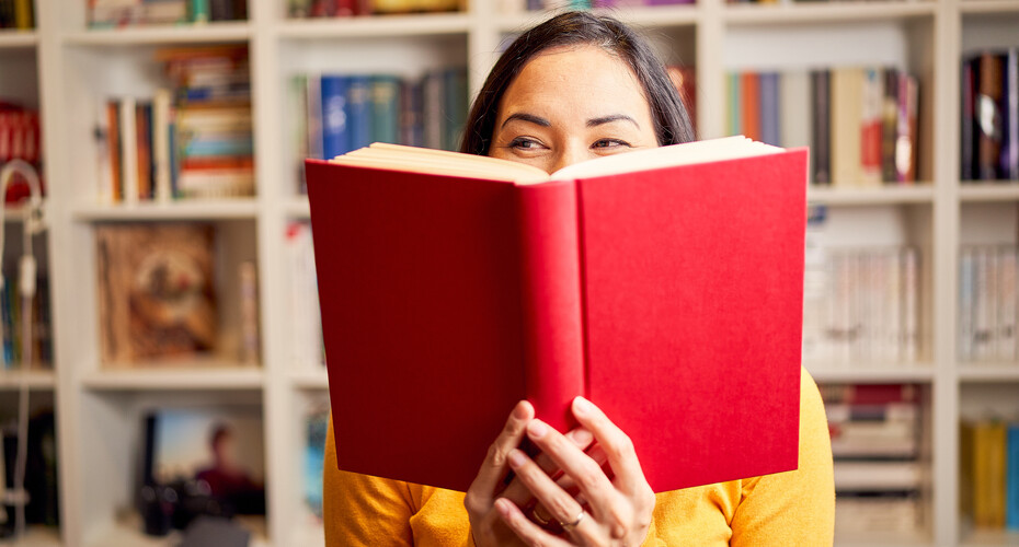 Girl in library reading red book